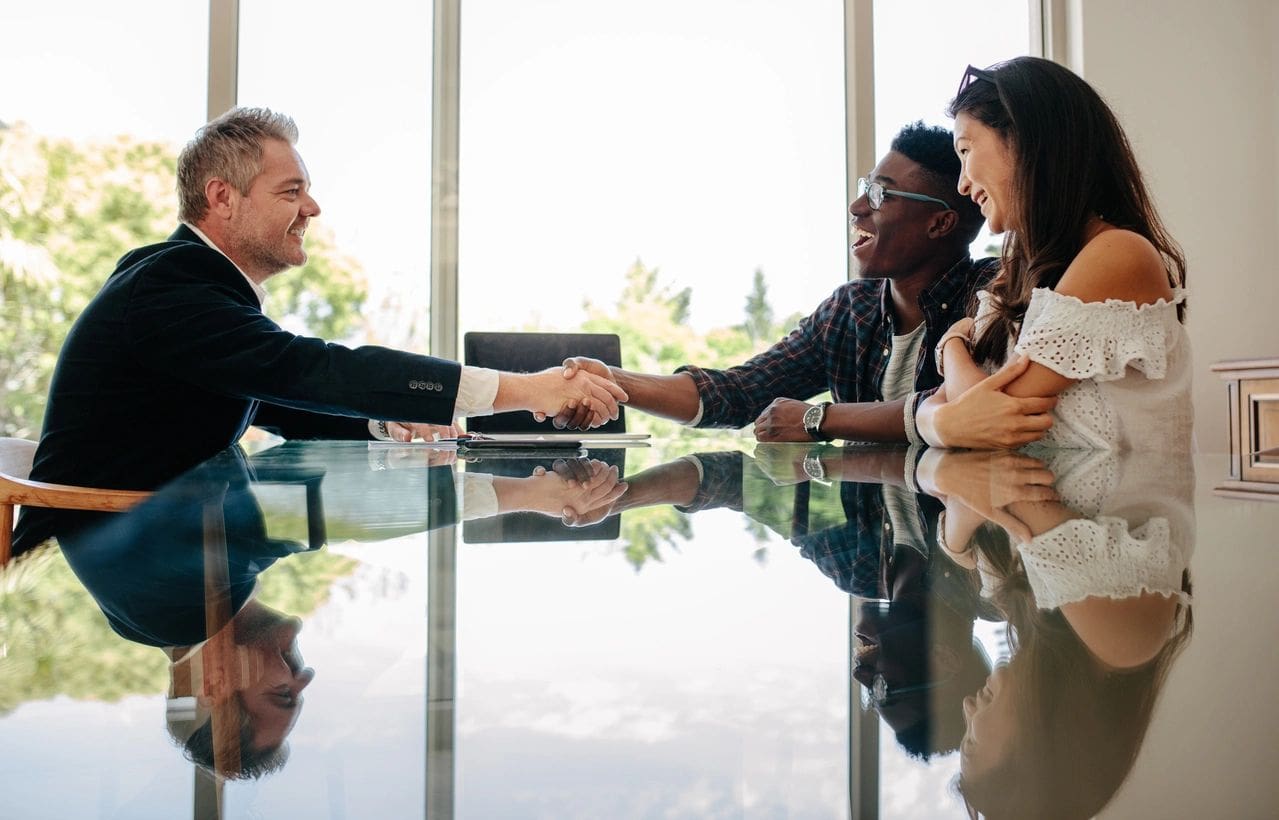 A group of people sitting around a table shaking hands.